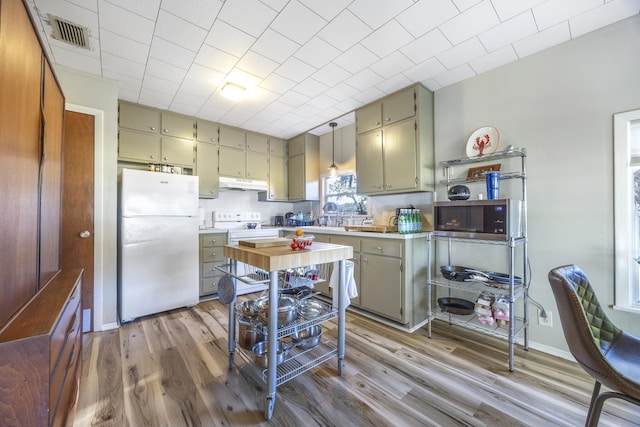 kitchen featuring light hardwood / wood-style flooring, hanging light fixtures, white appliances, and sink