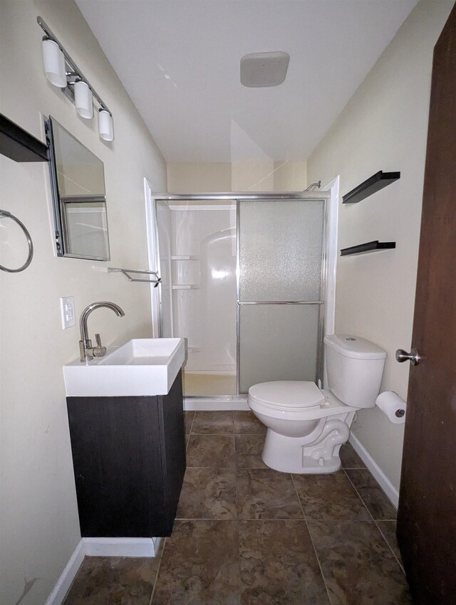 bathroom featuring vanity, a shower with shower door, and toilet