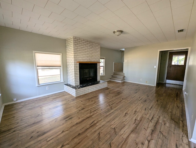 unfurnished living room with hardwood / wood-style flooring and a brick fireplace