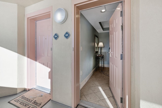 corridor featuring baseboards and light tile patterned flooring