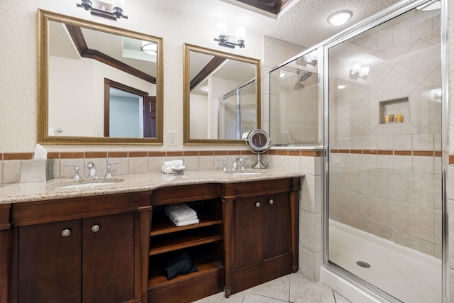 bathroom featuring a sink, double vanity, a stall shower, and a textured ceiling