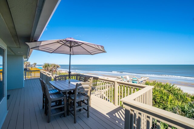 wooden terrace featuring a beach view and a water view