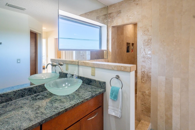 bathroom with tiled shower and vanity