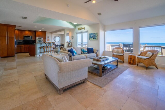 living room featuring ceiling fan, light tile patterned floors, a water view, and lofted ceiling