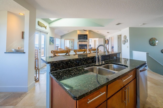 kitchen featuring a textured ceiling, sink, vaulted ceiling, and an island with sink