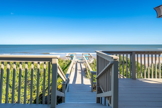 wooden terrace featuring a water view and a beach view