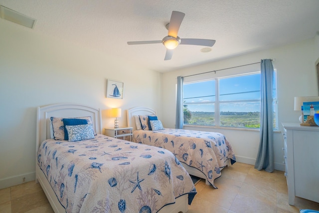 bedroom with ceiling fan, light tile patterned flooring, and a textured ceiling