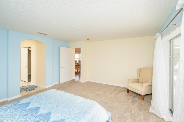 209 Lions Gate Dr, Saint Augustine, FL 32080 - bedroom with a textured ceiling, baseboards, light colored carpet, visible vents, and arched walkways