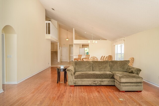 209 Lions Gate Dr, Saint Augustine, FL 32080 - living area with high vaulted ceiling, light wood-style floors, a chandelier, baseboards, and arched walkways