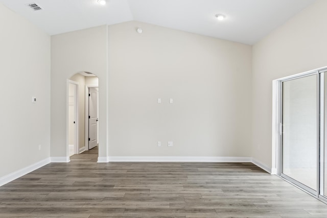 unfurnished room with vaulted ceiling, wood finished floors, arched walkways, and visible vents