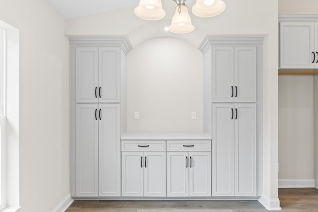 interior space featuring baseboards, light wood-type flooring, and an inviting chandelier