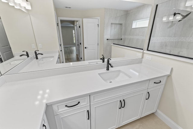 full bath with baseboards, visible vents, vanity, and walk in shower