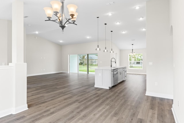 unfurnished living room with a sink, wood finished floors, baseboards, a chandelier, and vaulted ceiling