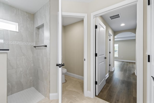 full bathroom with toilet, a walk in shower, visible vents, and baseboards