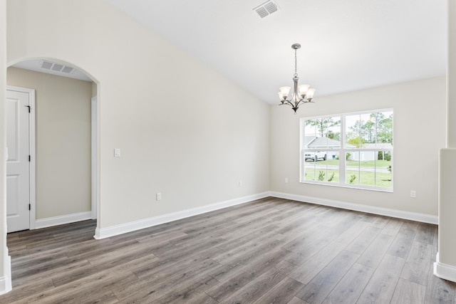 spare room featuring arched walkways, visible vents, a chandelier, and wood finished floors