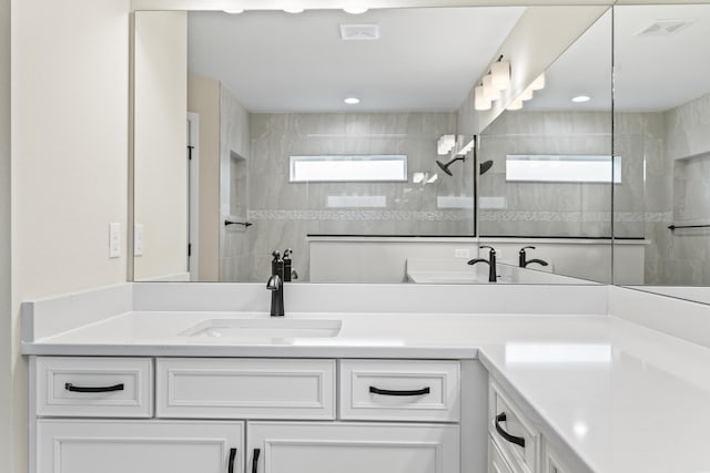 full bathroom with double vanity, visible vents, walk in shower, and a healthy amount of sunlight