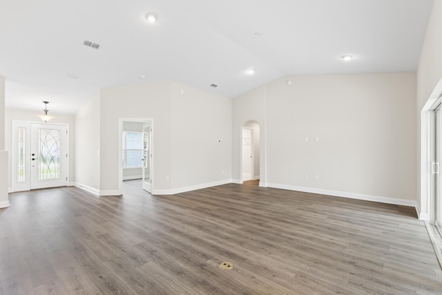 unfurnished living room featuring visible vents, baseboards, lofted ceiling, wood finished floors, and arched walkways