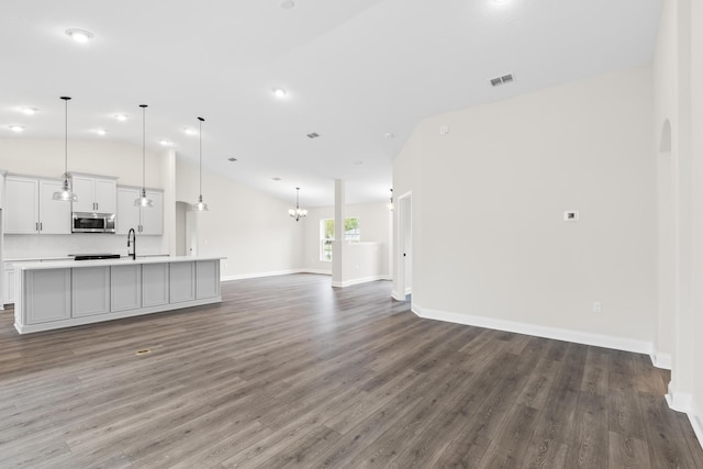 unfurnished living room featuring a sink, visible vents, baseboards, and wood finished floors