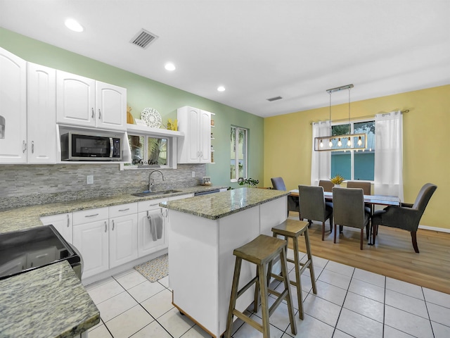 10 Seminole Dr, Saint Augustine, FL 32084 - kitchen with a sink, stainless steel microwave, light tile patterned floors, tasteful backsplash, and a kitchen island
