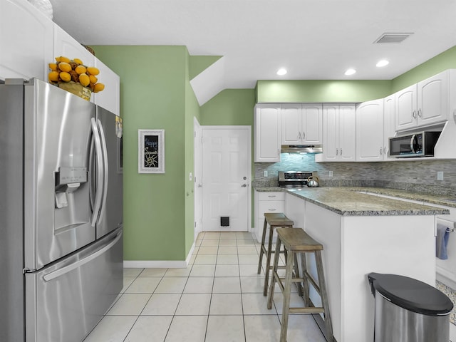 10 Seminole Dr, Saint Augustine, FL 32084 - kitchen with stainless steel appliances, under cabinet range hood, decorative backsplash, white cabinetry, and light tile patterned flooring