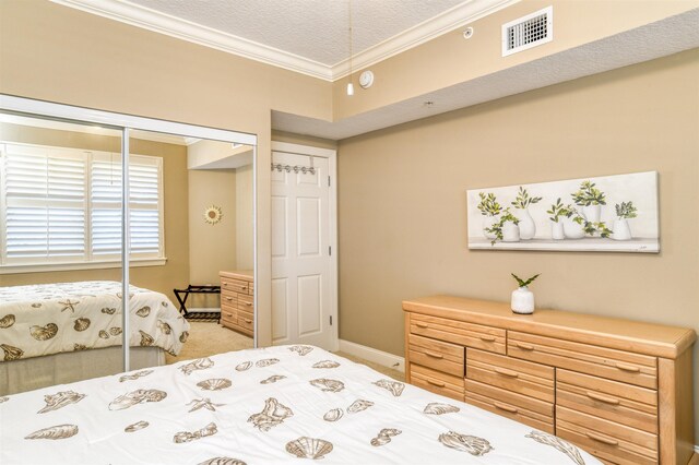 carpeted bedroom with a closet, a textured ceiling, and crown molding