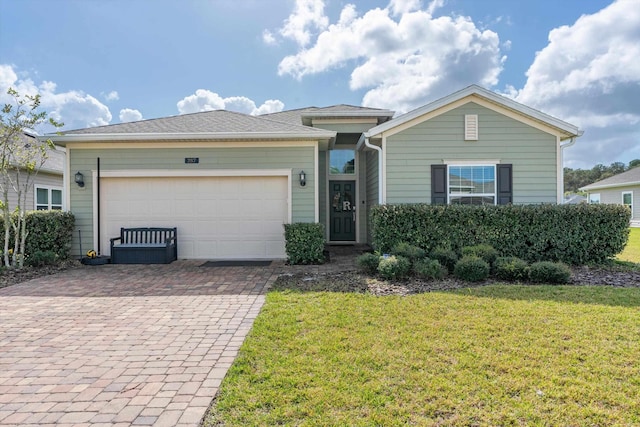 ranch-style home with a front lawn, decorative driveway, and an attached garage