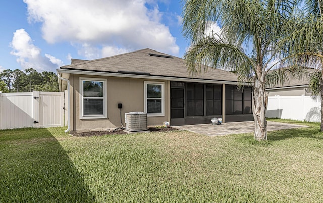 back of property featuring a lawn, a sunroom, a patio, and central AC