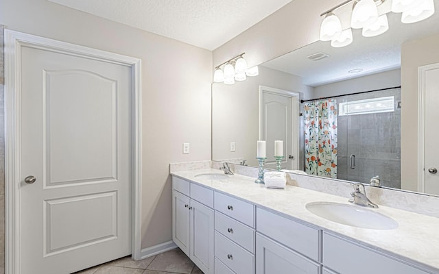 bathroom featuring tile patterned floors, vanity, a shower with door, and a textured ceiling