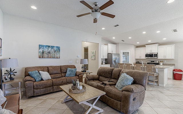 tiled living room with a textured ceiling, vaulted ceiling, and ceiling fan