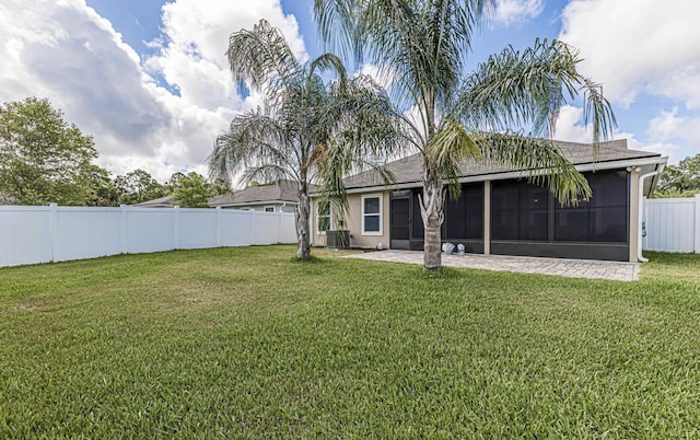 rear view of property with central AC, a lawn, and a sunroom