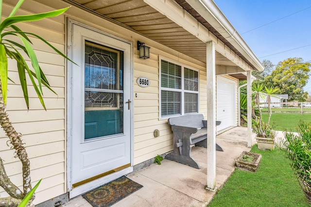 view of exterior entry with a yard and a garage