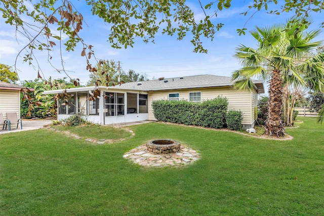 rear view of property with a sunroom, a lawn, and a fire pit