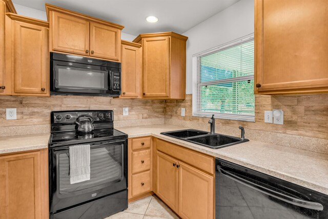 kitchen with sink, light tile patterned floors, black appliances, and decorative backsplash