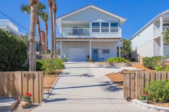 view of front of property featuring an attached garage, concrete driveway, a balcony, and fence