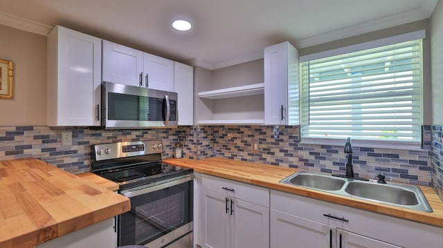 kitchen featuring butcher block counters, white cabinetry, sink, stainless steel appliances, and backsplash