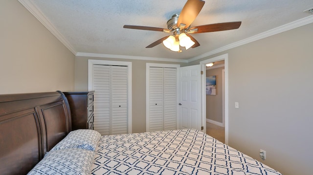 carpeted bedroom featuring a textured ceiling, two closets, ceiling fan, and crown molding