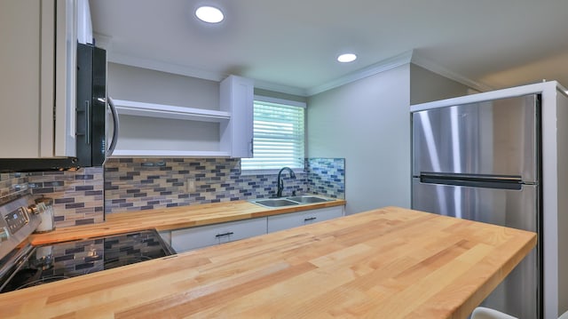 kitchen with stainless steel refrigerator, butcher block counters, sink, backsplash, and ornamental molding