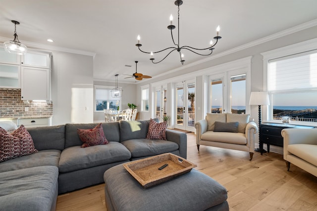 living room with ornamental molding, ceiling fan with notable chandelier, and light hardwood / wood-style flooring