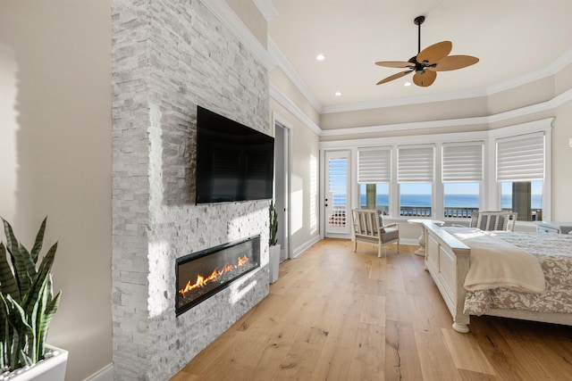 bedroom with light wood-type flooring, crown molding, a fireplace, and access to outside