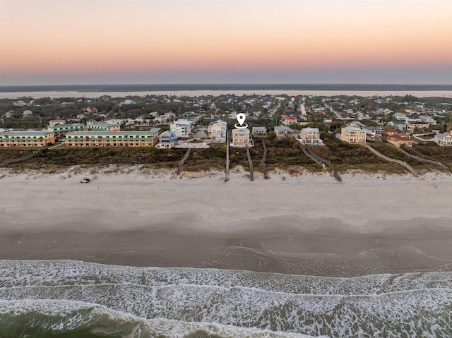 aerial view at dusk with a view of the beach and a water view