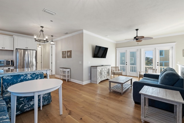 living room featuring crown molding, ceiling fan with notable chandelier, and light wood-type flooring