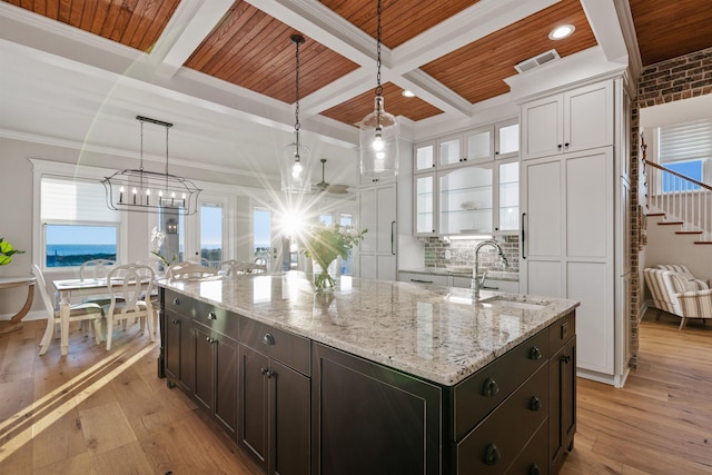 kitchen featuring pendant lighting, sink, an island with sink, and light hardwood / wood-style flooring