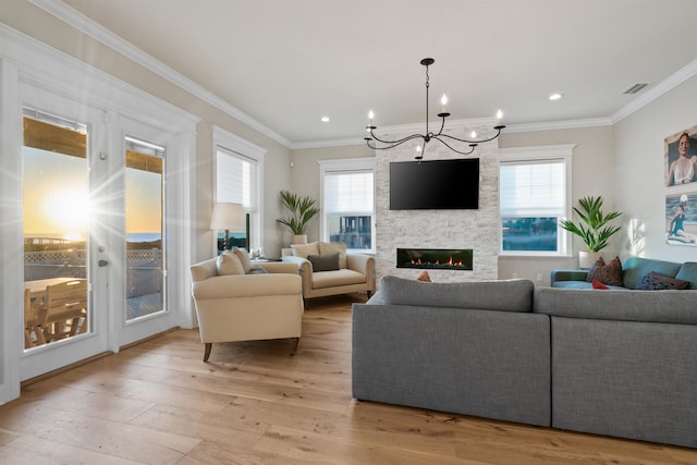 living room with ornamental molding, a healthy amount of sunlight, a fireplace, and light hardwood / wood-style flooring