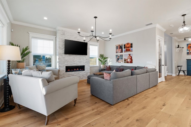 living room featuring crown molding, a stone fireplace, an inviting chandelier, and light wood-type flooring