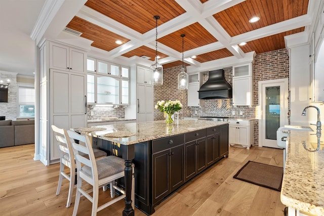 kitchen with custom exhaust hood, pendant lighting, white cabinets, and light stone counters