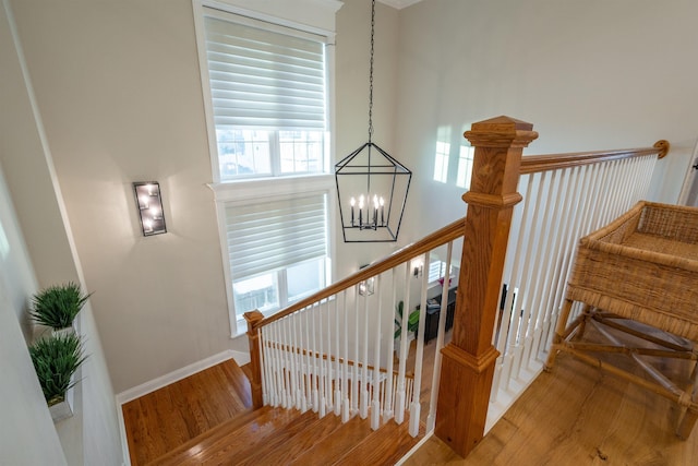 staircase with hardwood / wood-style floors and a chandelier