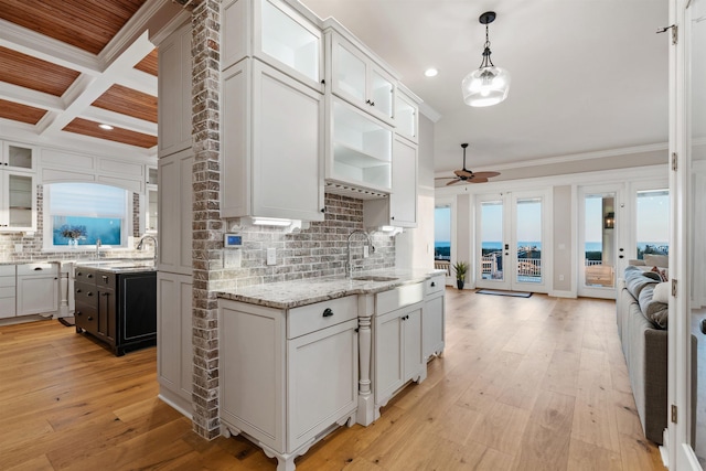 kitchen with sink, white cabinetry, crown molding, decorative light fixtures, and light hardwood / wood-style floors