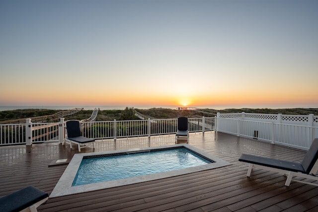 pool at dusk featuring a wooden deck