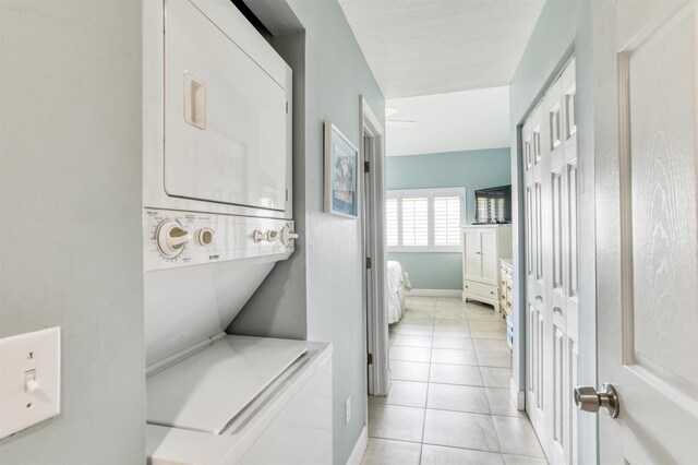 washroom featuring stacked washer and dryer and light tile patterned flooring