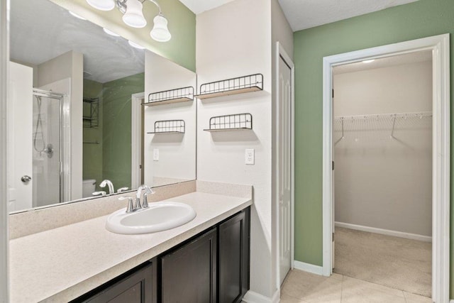 117 Mission Cove Cir, Saint Augustine, FL 32084 - bathroom featuring a shower stall, tile patterned flooring, vanity, a walk in closet, and baseboards